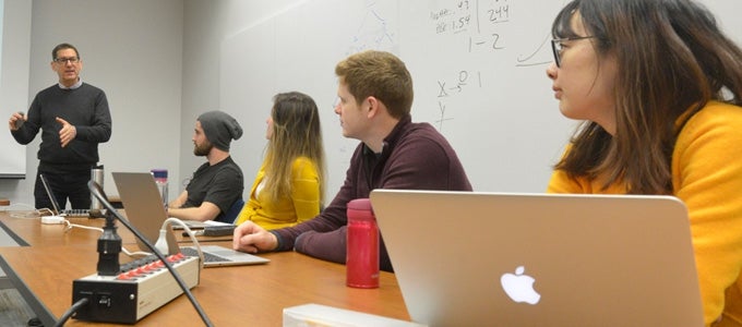 A professor leads his class in discussion 